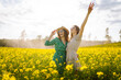 © maxbelchenko - Two friends enjoy a sunny day in a vibrant yellow flower field wearing stylish outfits and sunglasses. Nature, vacation, relax and lifestyle. Summer landscape.