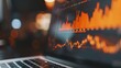 © MD Media - Close-up of financial growth charts on a laptop screen during a business meeting, open laptop displaying stock market data on the screen, with financial charts and graphs in orange tones