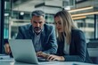 © yj - Two busy professional executives team using laptop in modern office. Business man and woman leaders managers working on computer at work desk having conversation on financial project at meeting.