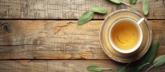 Poster - Top view of an herb infused tea in a cup alongside sage on a wooden table providing ample copy space image