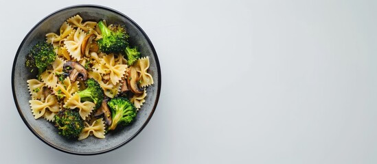 Poster - Top down view of a dish featuring farfalle pasta roasted broccoli and sauteed mushrooms in a bowl on a white backdrop with empty space for text or images. Creative banner. Copyspace image