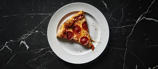 Poster - Pizza slice being bitten on a white plate against a black marble backdrop with copy space image