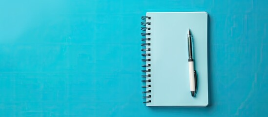 Poster - Notebook and pen on a blue background with copy space image