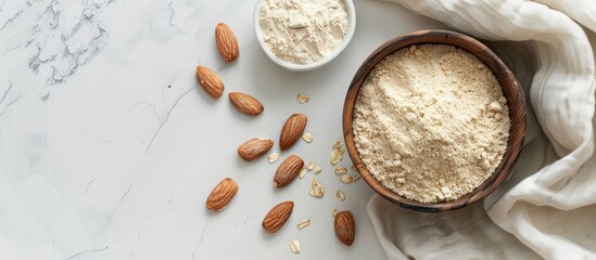 Poster - Top view of almond flour in a bowl and nuts on a white marble table with copy space image available