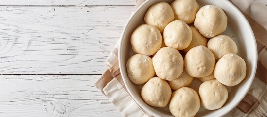 Poster - Top down view of scrumptious dough balls in a baking dish on a white wooden surface with ample space for text beside the image