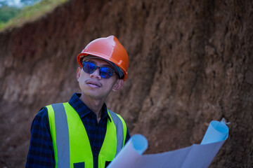 young male construction worker carrying blueprints, reading and analyzing them