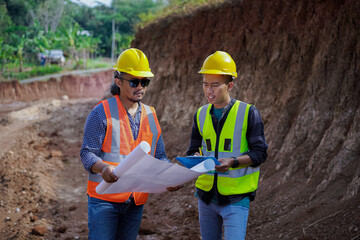 two young male construction workers are surveying using blueprints in the field