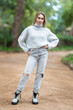 © KONSTANTIN SHISHKIN - Attractive young woman posing in the park wearing jeans and sweater