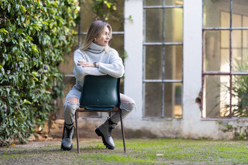 Young woman wearing casual clothes posing sitting on a chair in a garden