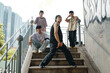 © DragonImages - Group of young men posing on staircase surrounded by urban landscape and graffiti showcasing hip-hop culture and fashion captured in energetic stance