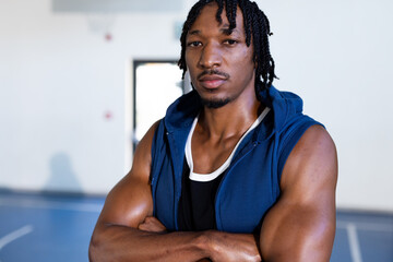 Wall Mural - Confident basketball player in gym crossing arms, wearing athletic gear