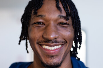 Smiling african american man with braided hair looking at camera, close-up portrait