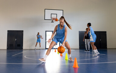 Wall Mural - Dribbling basketball around cones, female basketball player practicing in gym