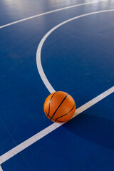 Wall Mural - Basketball on court, resting on blue floor with white lines, copy space