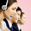 © vgstudio - Contact center servise concept image. Call centre phone operators working at workplace together. Wide banner composition with copy space free area. Rose pink background.