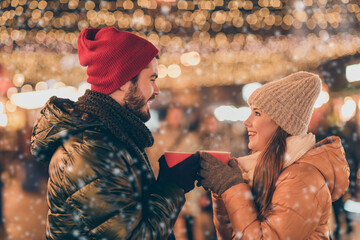 Wall Mural - Photo of two people couple clink hot coffee beverage cup under evening x-mas tradition outside illumination wear season coats