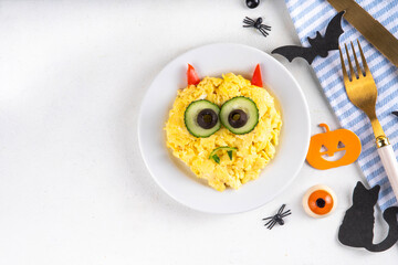 Halloween breakfast scrambled eggs shaped and decorated like cute monster, with fresh vegetables, funny kids Halloween food simple recipe idea