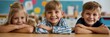 © gunzexx png and bg - Three young children sit at a table in a classroom, smiling brightly and radiating joy, with colorful classroom decorations and art supplies around them.