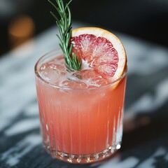 Sticker - Pink cocktail with ice, grapefruit slice, and rosemary garnish in a glass on marble surface.