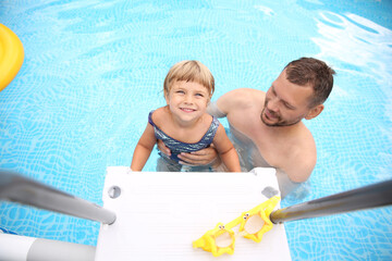 Wall Mural - Happy daughter and her father near ladder in swimming pool, above view