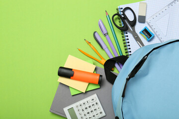 Wall Mural - Backpack and different school stationery on light green background, flat lay. Space for text