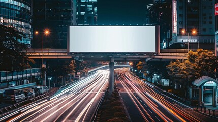 Illuminated urban highway with light trails beneath a massive blank billboard, framed by skyscrapers and city lights in a bustling metropolis at night.