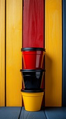 Wall Mural - Three cups stacked on top of each other, one red, one black, and one yellow