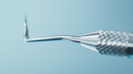 Close-up of a sleek, metallic dental instrument with a complex tip, highlighting the fine craftsmanship against a blue gradient background.