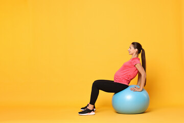 Sticker - Beautiful pregnant woman doing exercises on fitball against yellow background