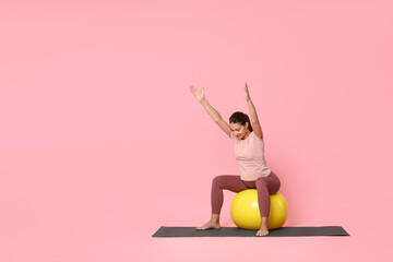 Canvas Print - Beautiful pregnant woman doing exercises on fitball against pink background, space for text