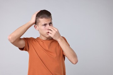 Canvas Print - Young man suffering from sinusitis on light grey background, space for text