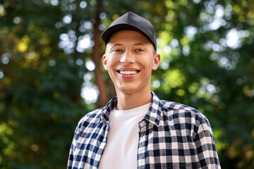 Wall Mural - Portrait of smiling man in baseball cap outdoors. Space for text