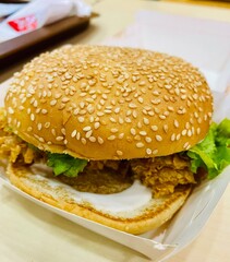 hamburger on wooden background. Chicken burger with salad and mayonnaise. closeup of sloppy assembled or cooked burger taken away from restaurant.