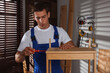 © New Africa - Man repairing wooden stool with screwdriver indoors