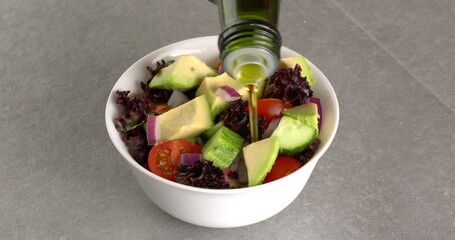 Poster - Healthy salad of fresh vegetables in a plate on a gray background. Olive oil is poured into a plate with salad. Close-up footage on the rotating table.