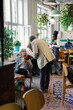 © Oleksii Syrotkin/Stocksy - Woman with flowers looking at man near waitress and visitors in cafe