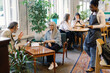 © Oleksii Syrotkin/Stocksy - Waitress carrying coffee and cake to senior couple talking in cafe