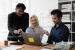 © Kritdanai - Collaborative Brainstorming: A diverse team of professionals, including a woman wearing a headscarf, collaborates around a laptop in a modern office setting. The image captures the dynamism and inclus