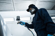 © Rabizo Anatolii - Car painter is painting automobile. Mechanic from vehicle maintenance service is spreading paint on car using dark spray and paint gun.