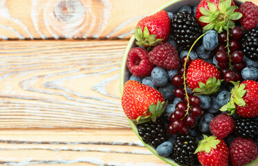 Wall Mural - Mix of ripe colorful berries in bowl photography . Blueberry , strawberry , raspberry , blackberry and red currant . Top view