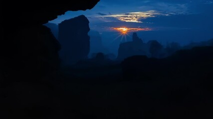 Poster - Sunlight shines through a dark cave onto a mysterious landscape enveloped in fog, with mountains and rocks creating a dramatic and enchanting scenery perfect for exploration and adventure