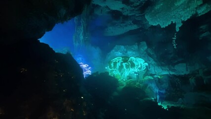 Aufkleber - Mystical underwater cave with glowing green water is being explored by someone holding a light. The cave is dark and mysterious, with strange rock formations