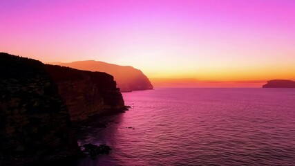 Poster - The sun sets over the ocean, casting a warm orange glow on the water and painting the sky with vibrant colors as clouds dance in the evening sky, creating a beautiful seascape