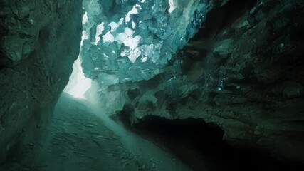 Canvas Print - Sunbeam illuminating turquoise water in a mysterious cave, creating a magical atmosphere. Dark rocks add to the surreal feel, inviting you on an underground adventure