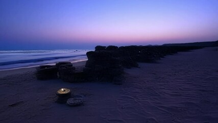 Poster - The sun sets over the beach, turning it into a mystical landscape with scattered rocks