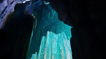 Poster - Mesmerizing underground scene showing a cave illuminated by turquoise and purple light, creating a magical and otherworldly atmosphere