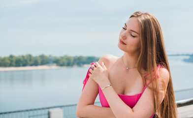 Youth concept. Nice beautiful Slavic beauty with long blonde hair, girl in pink top and jeans outdoor portrait