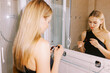 © Alexey Kuzma/Stocksy - young woman near the mirror doing makeup
