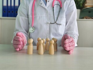  doctor protects pawns group with hands at table. Medical worker performs strategic health care policy concepts in clinic office