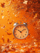 © zphoto83 - A classic silver alarm clock sits amidst swirling orange autumn leaves, evoking a warm seasonal feeling. The scene emphasizes the beauty of fall colors and the passage of time
